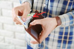 Uomo che controlla nel portafoglio quali banconote ha con una freccia rossa che le indica